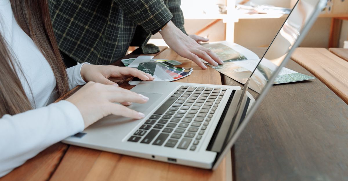criação de site em Pederneiras — Close-up de mãos colaborando em um laptop em um escritório de startup, focando no trabalho em equipe.